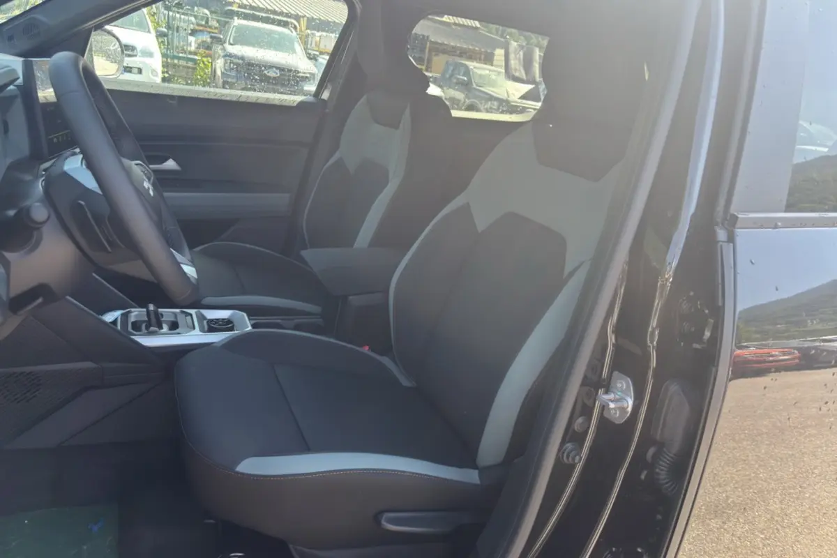 Vue intérieure côté conducteur du Dacia Duster Hybrid-G 150 4x4 noir nacré, mettant en valeur les sièges bicolores et la console centrale.