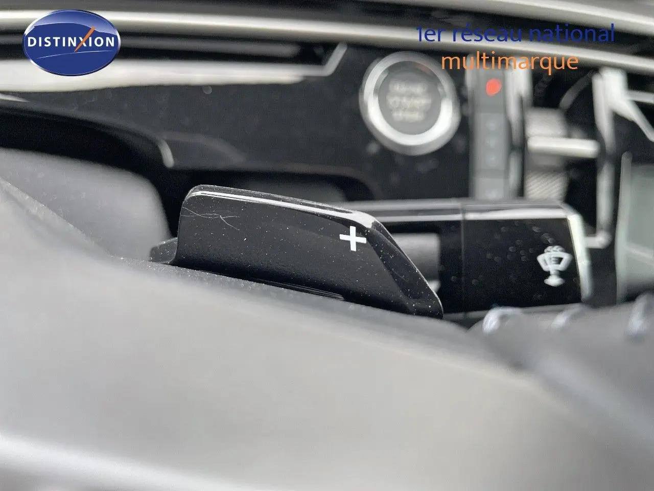 Gros plan sur la palette de changement de vitesse "+" du volant d'un Peugeot 3008 Hybrid noir métal, intérieur moderne.