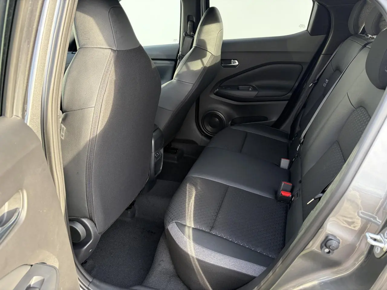 Vue intérieure côté droit sur la banquette arrière noire en tissu et TEP du Nissan Juke II 1.6 Hybrid 2025.
