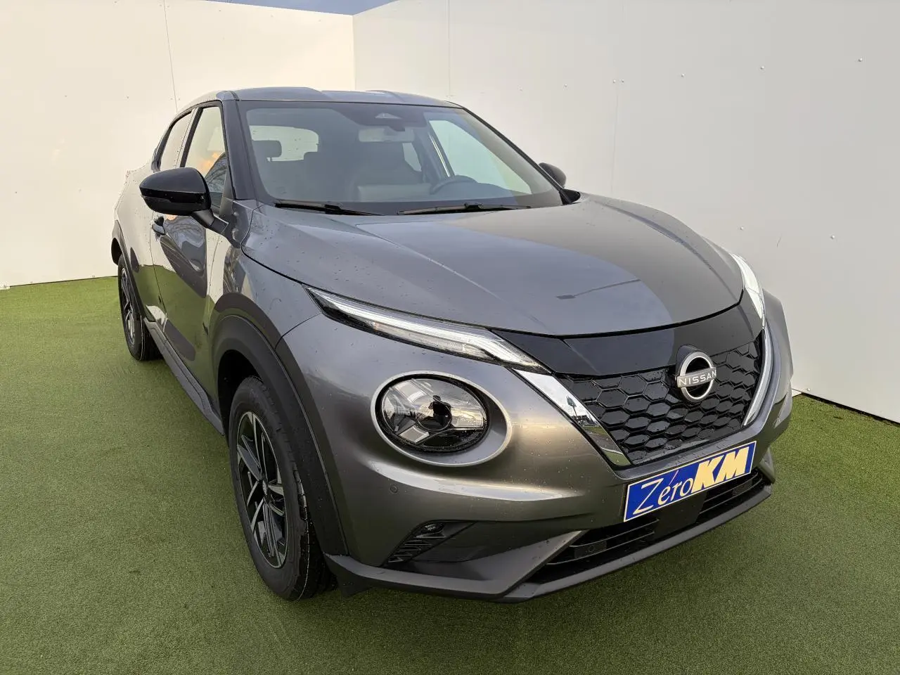 Nissan Juke II 1.6 Hybrid noir métal vu en 3/4 avant gauche avec calandre en nid d'abeille et phares LED ronds.