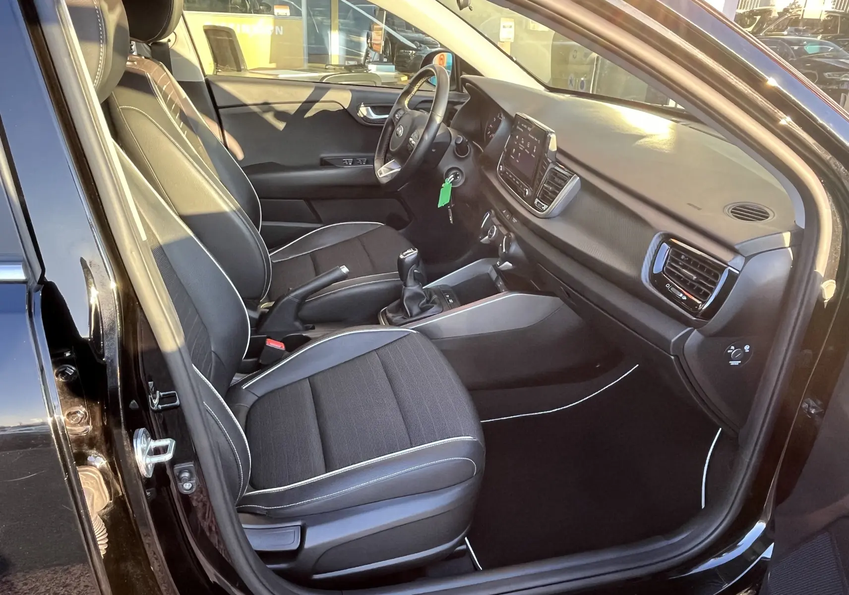 Intérieur de la KIA Rio 1.0 GDI 100 Hybrid GT Line 2021 noir, vue côté gauche avec sièges tissu et tableau de bord moderne.