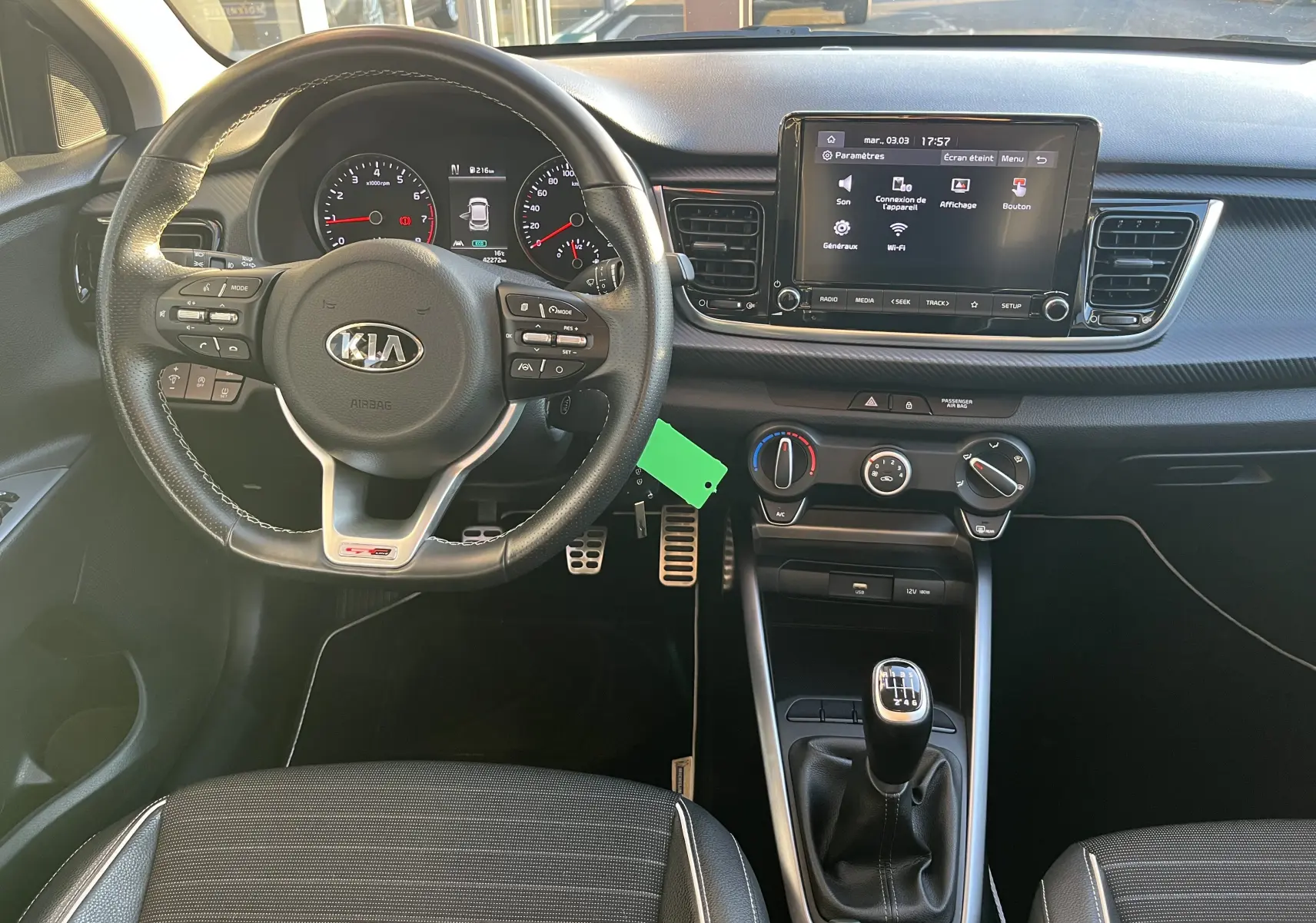 Vue intérieure frontale du poste de conduite de la KIA RIO noire 2021, avec volant multifonction et écran tactile central.