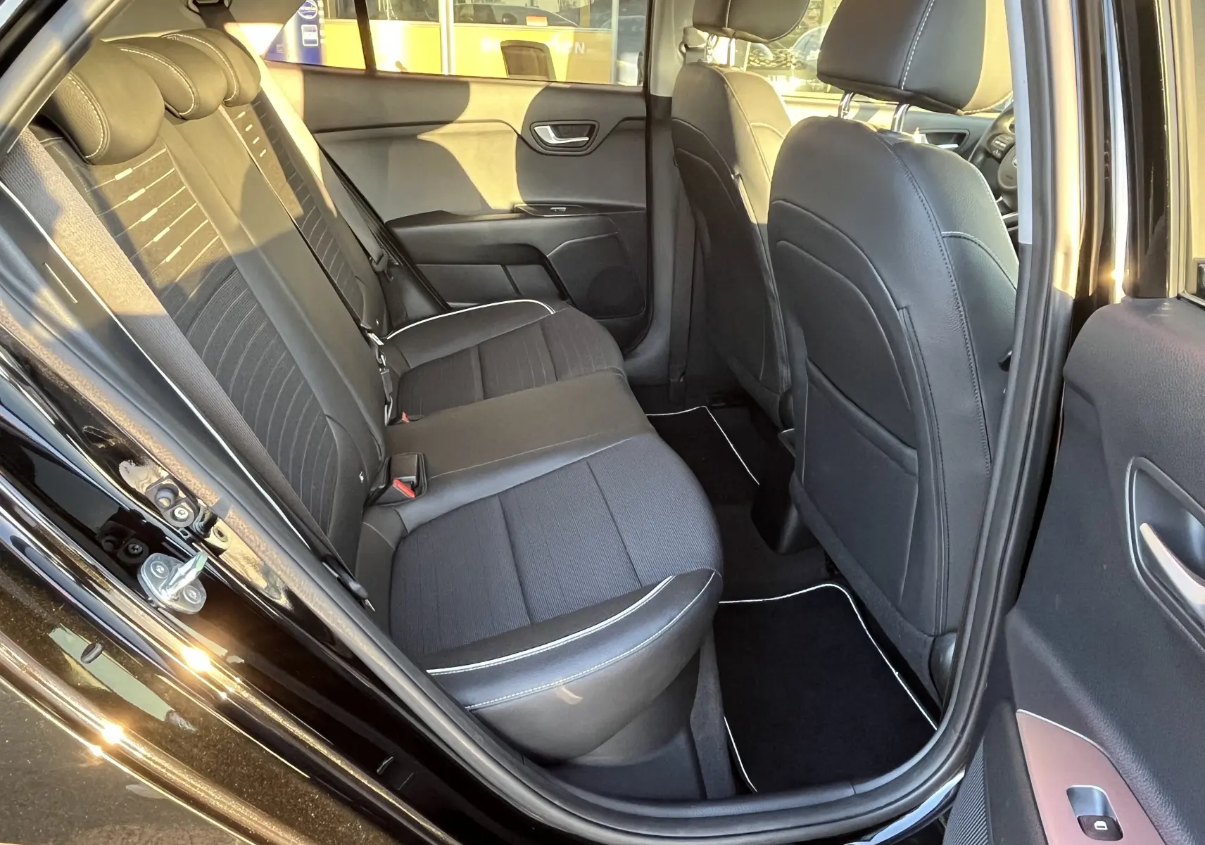 Vue intérieure côté gauche des sièges arrière noirs avec surpiqûres blanches d'une KIA RIO 1.0 GDI 100 HYBRID GT LINE 2021.