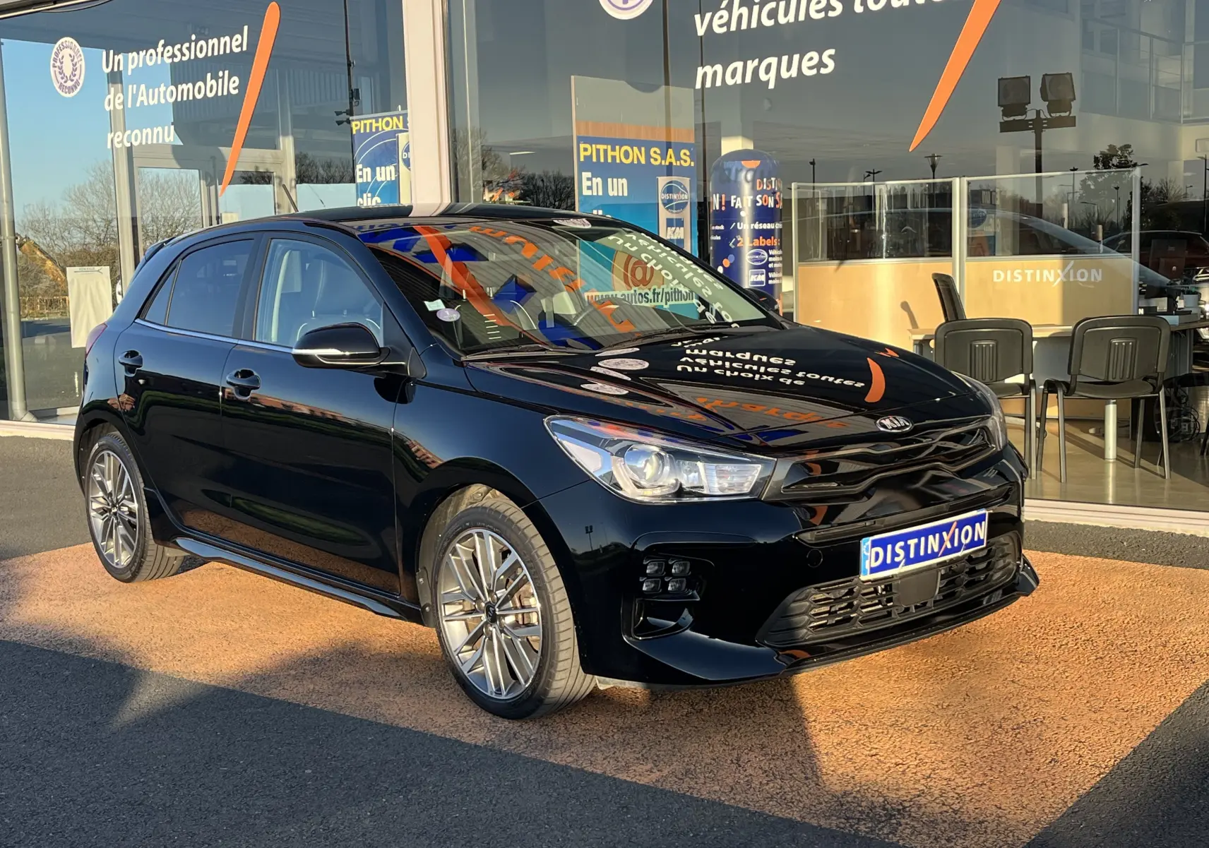 KIA RIO 1.0 GDI 100 HYBRID GT LINE noire vue 3/4 avant droit, avec jantes alliage et calandre distinctive.