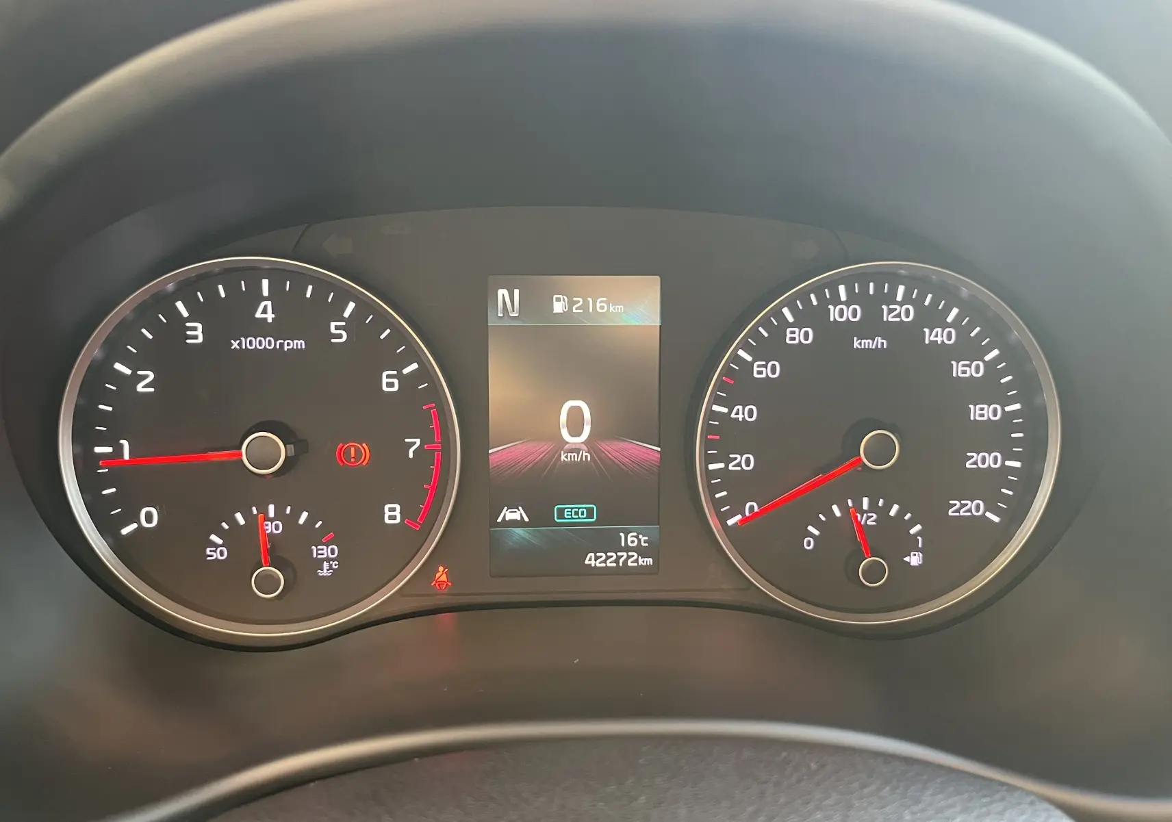 Tableau de bord de Kia Rio 2021 noir, affichage digital central et compteurs analogiques vitesse et régime moteur.