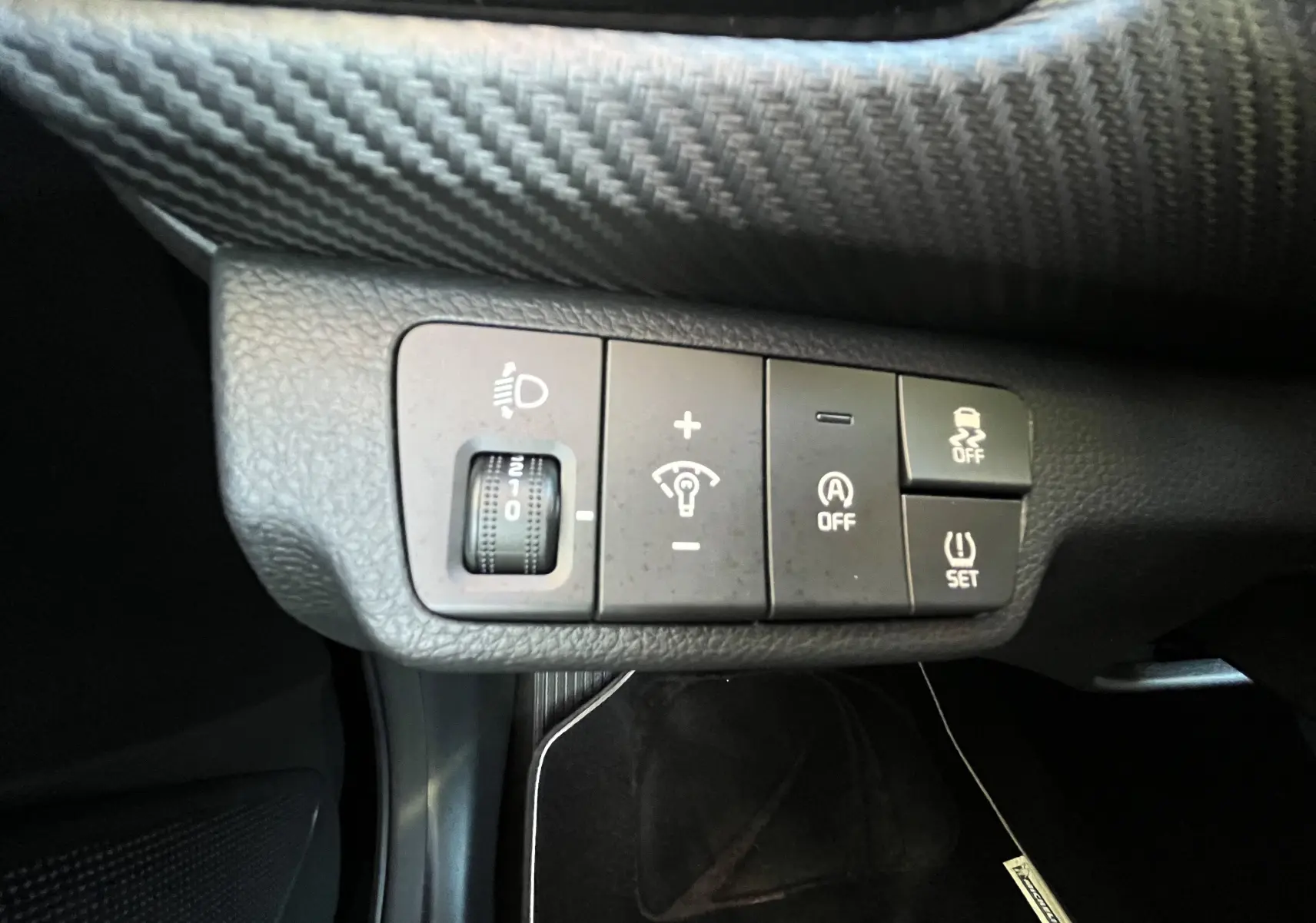 Gros plan sur les commandes de réglage d’éclairage et d’assistance du tableau de bord d’une Kia Rio noire 2021.
