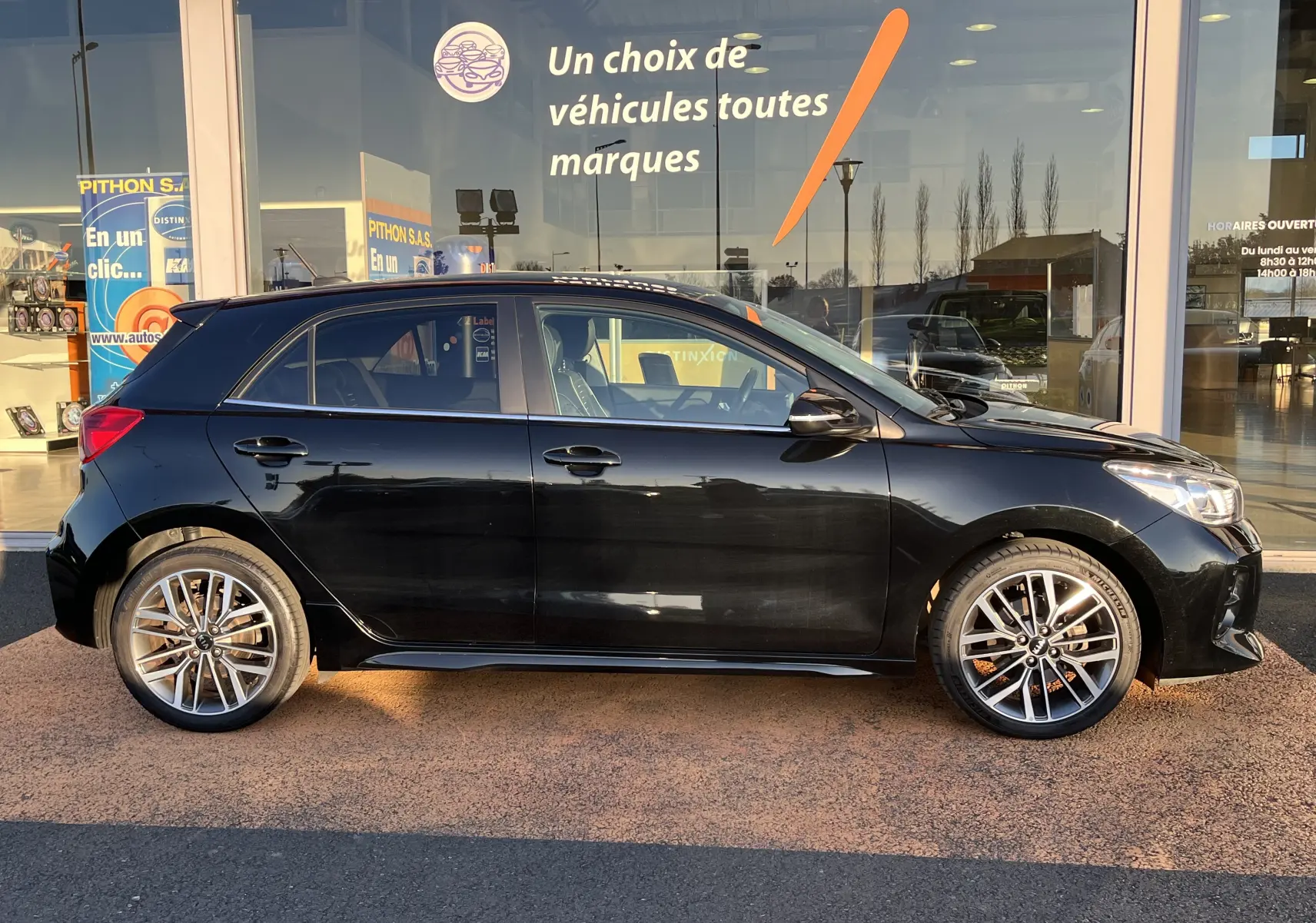 Profil côté gauche d'une KIA RIO 1.0 GDI 100 HYBRID GT LINE noire de 2021 avec jantes alliage 17 pouces et feux LED.