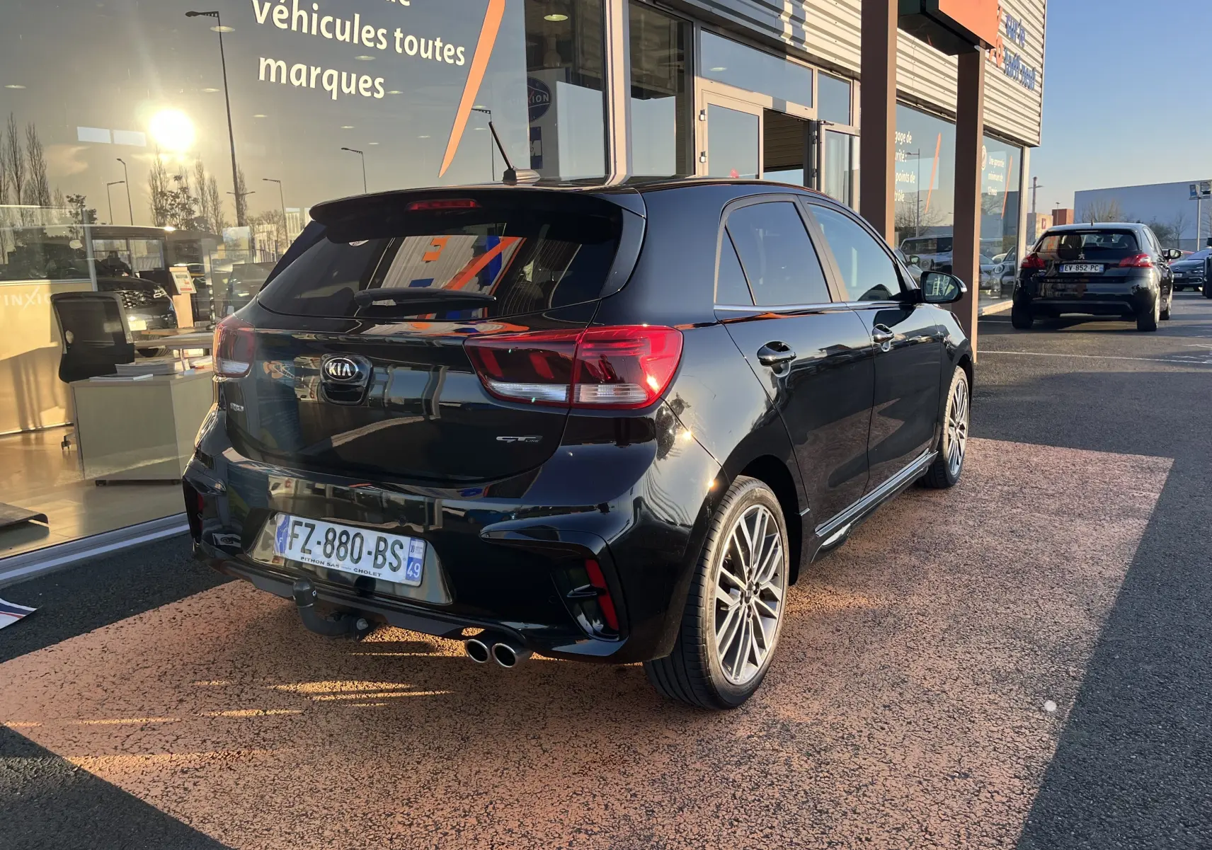 Vue 3/4 arrière droite d'une KIA Rio noire 2021 GT Line avec double sortie d'échappement et jantes alliage 17 pouces.