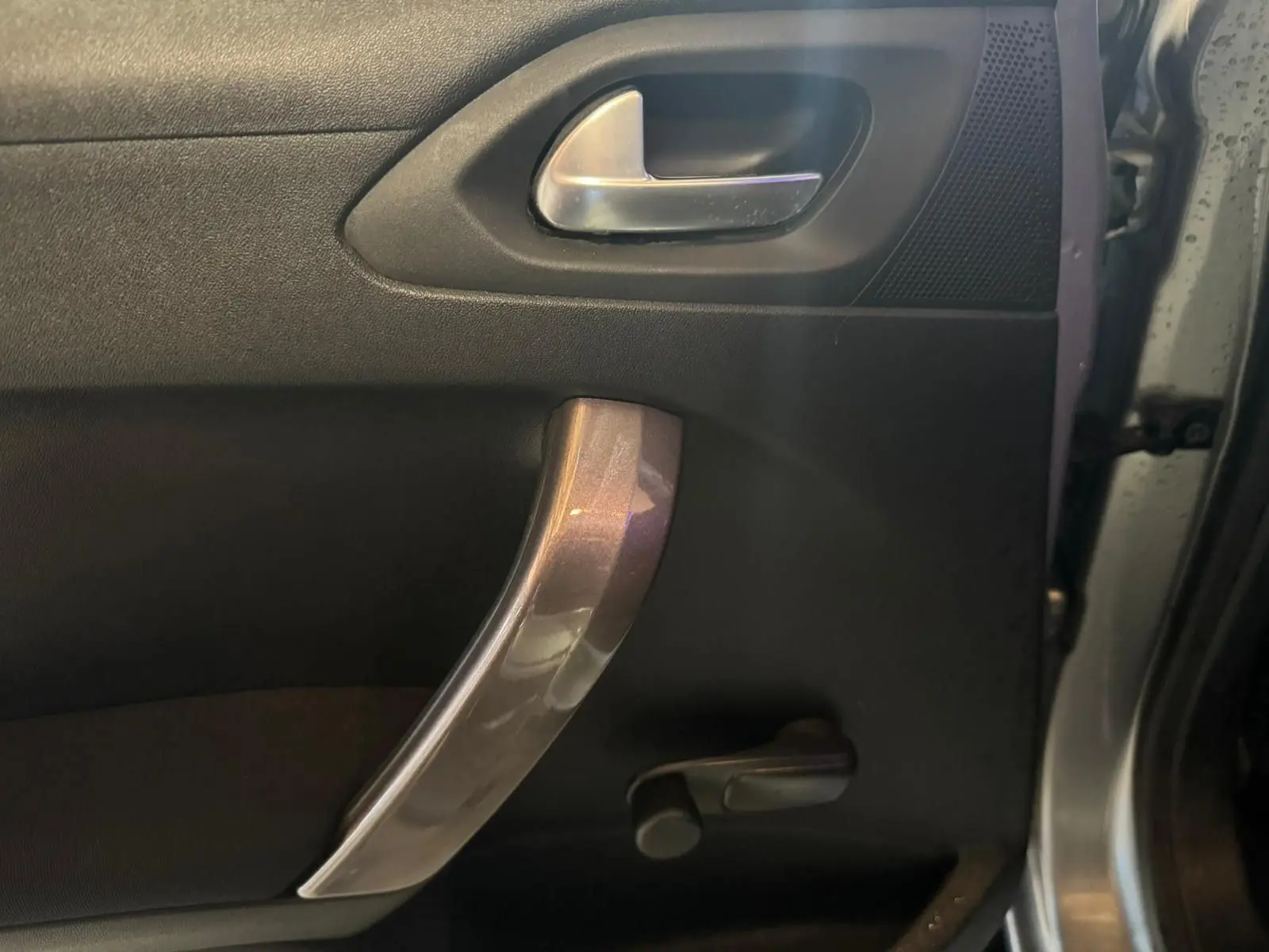 Détail de la poignée intérieure de porte côté gauche du Peugeot 2008 gris 2016 avec manivelle de vitre manuelle.