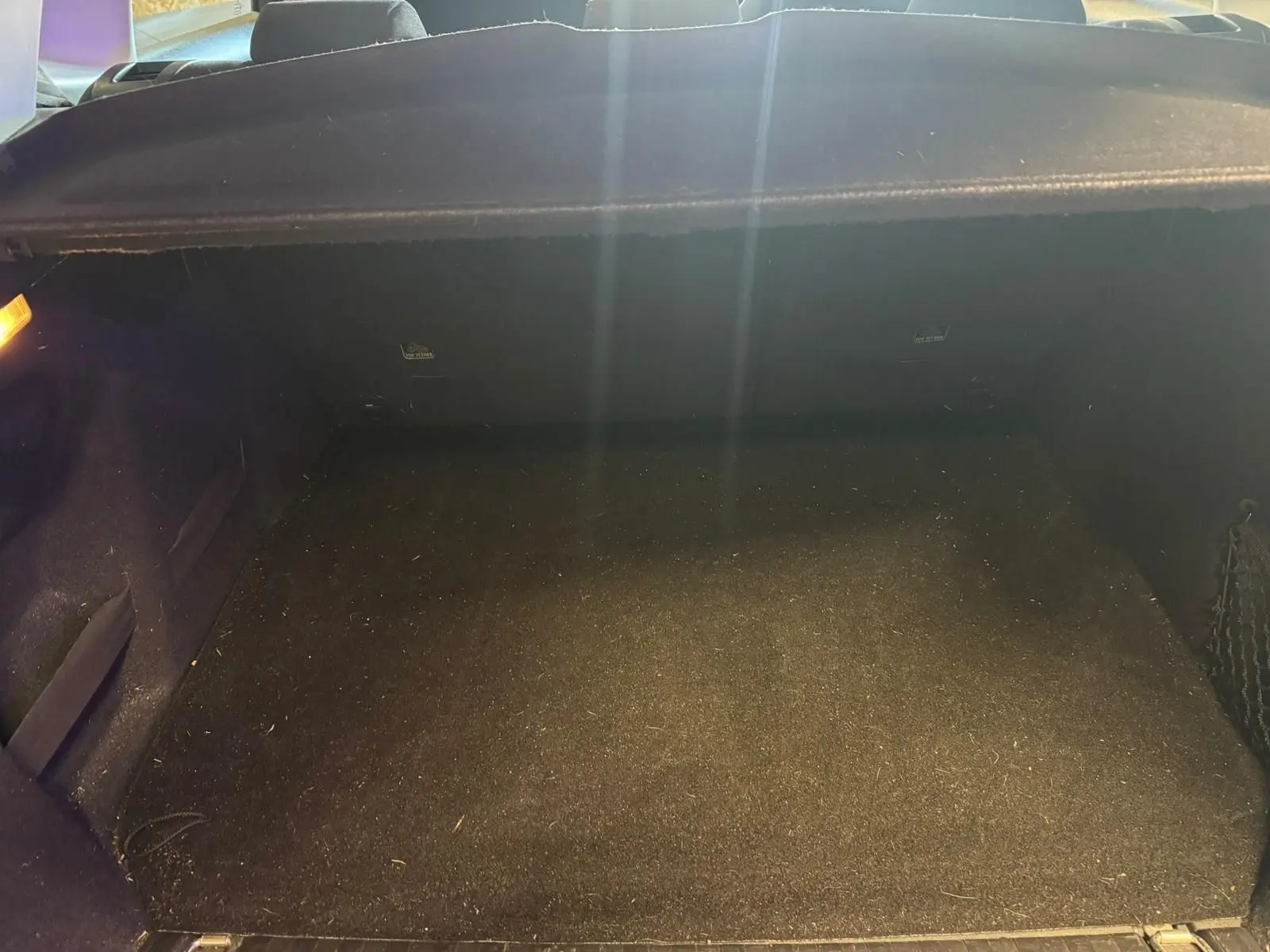 Coffre vide en vue intérieure arrière d'un Peugeot 2008 gris, montrant le tapis de sol et les parois noires.