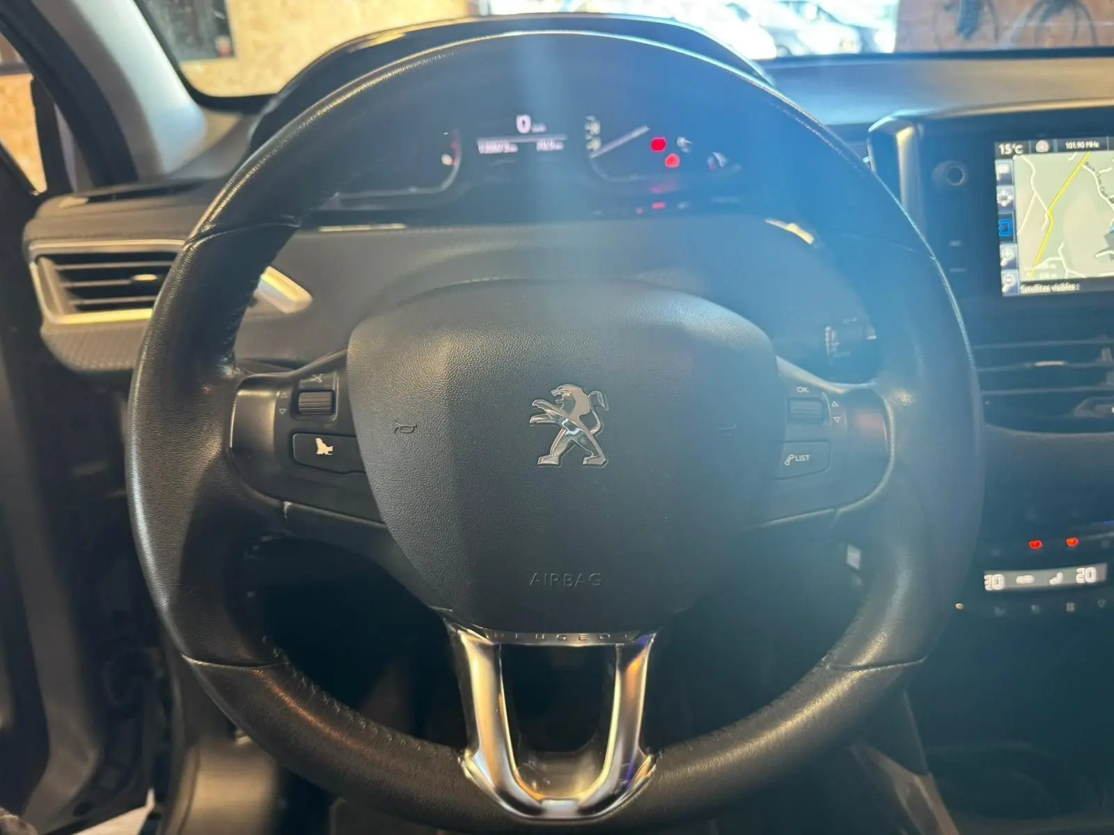 Vue rapprochée du volant noir de la Peugeot 2008 1.6 HDI 2016 avec tableau de bord et écran GPS visible.