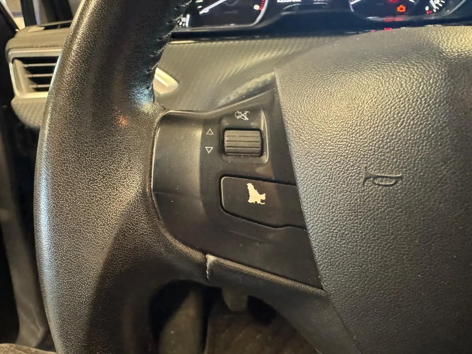 Gros plan sur le volant noir du Peugeot 2008 1.6 HDI 2016, avec commandes audio intégrées à gauche.