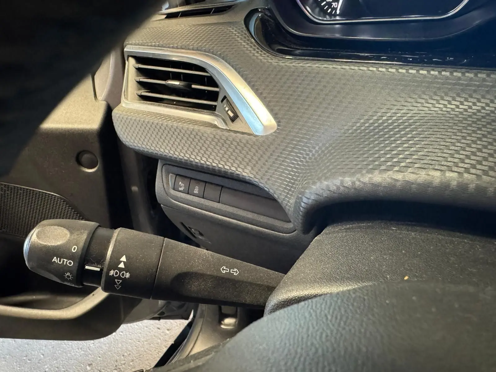 Gros plan sur la manette de clignotants à gauche du volant dans l’habitacle noir du Peugeot 2008 gris 2016.