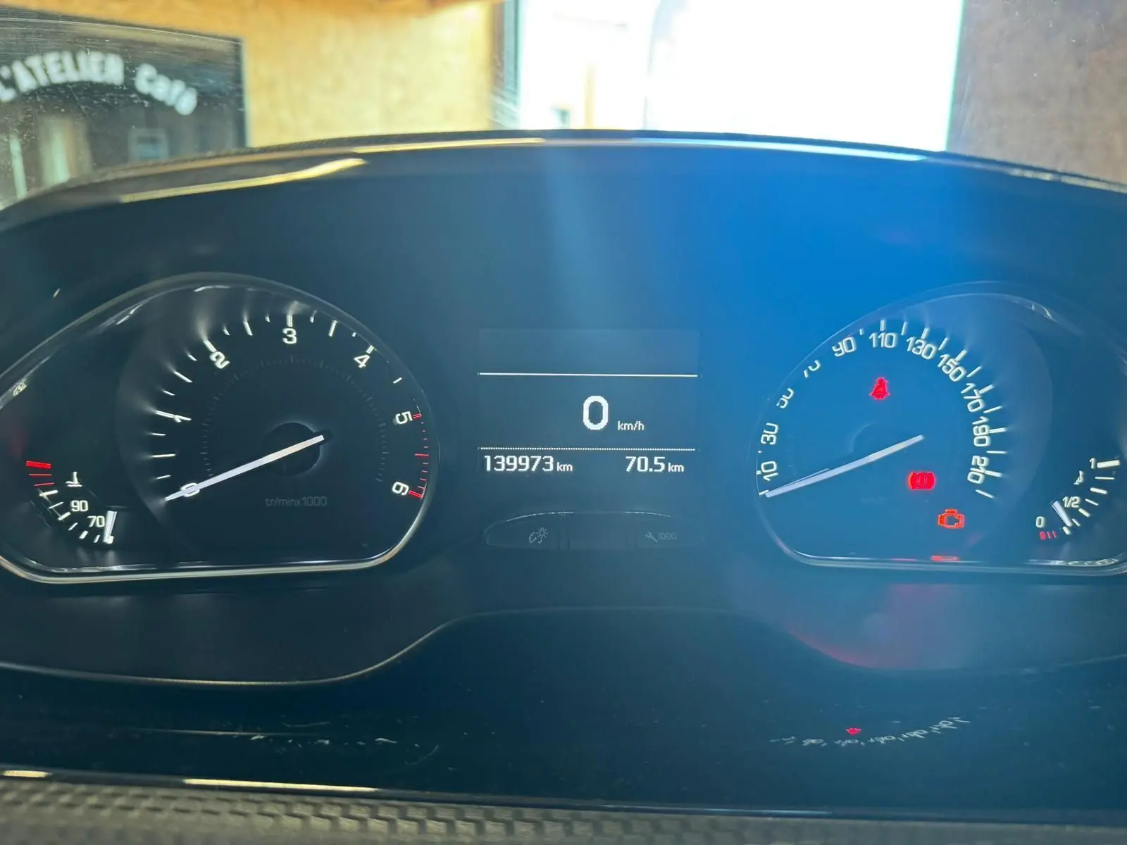 Vue rapprochée du tableau de bord du Peugeot 2008 gris, affichant le compteur à 0 km/h et 139973 km au total.