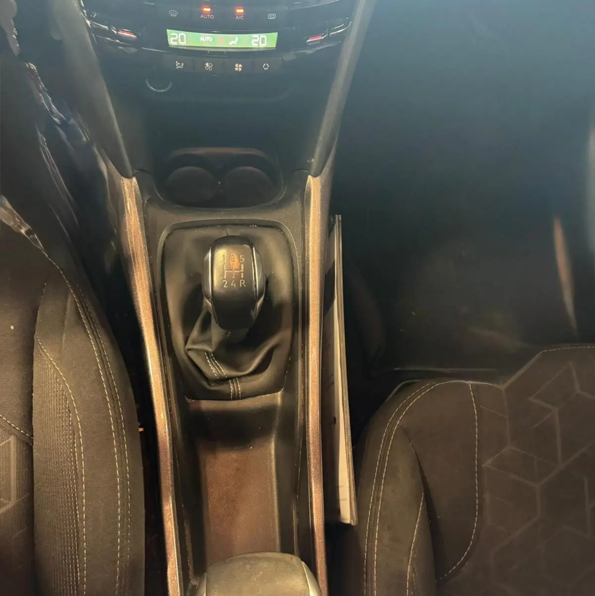 Vue plongeante sur la console centrale du Peugeot 2008 gris, mettant en valeur le levier de vitesse manuel et les sièges en tissu noir.