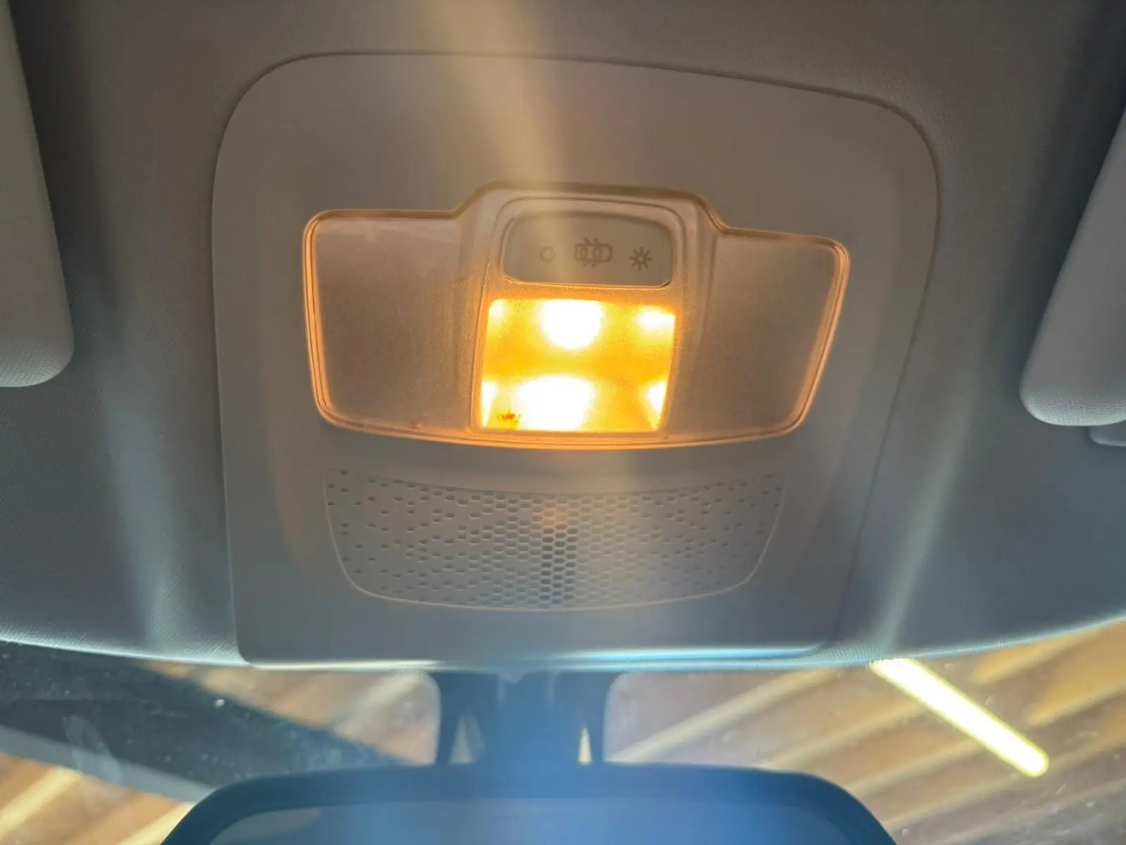 Plafonnier intérieur allumé vu de dessous dans un Peugeot 2008 gris diesel, version 2016, avec toit clair.