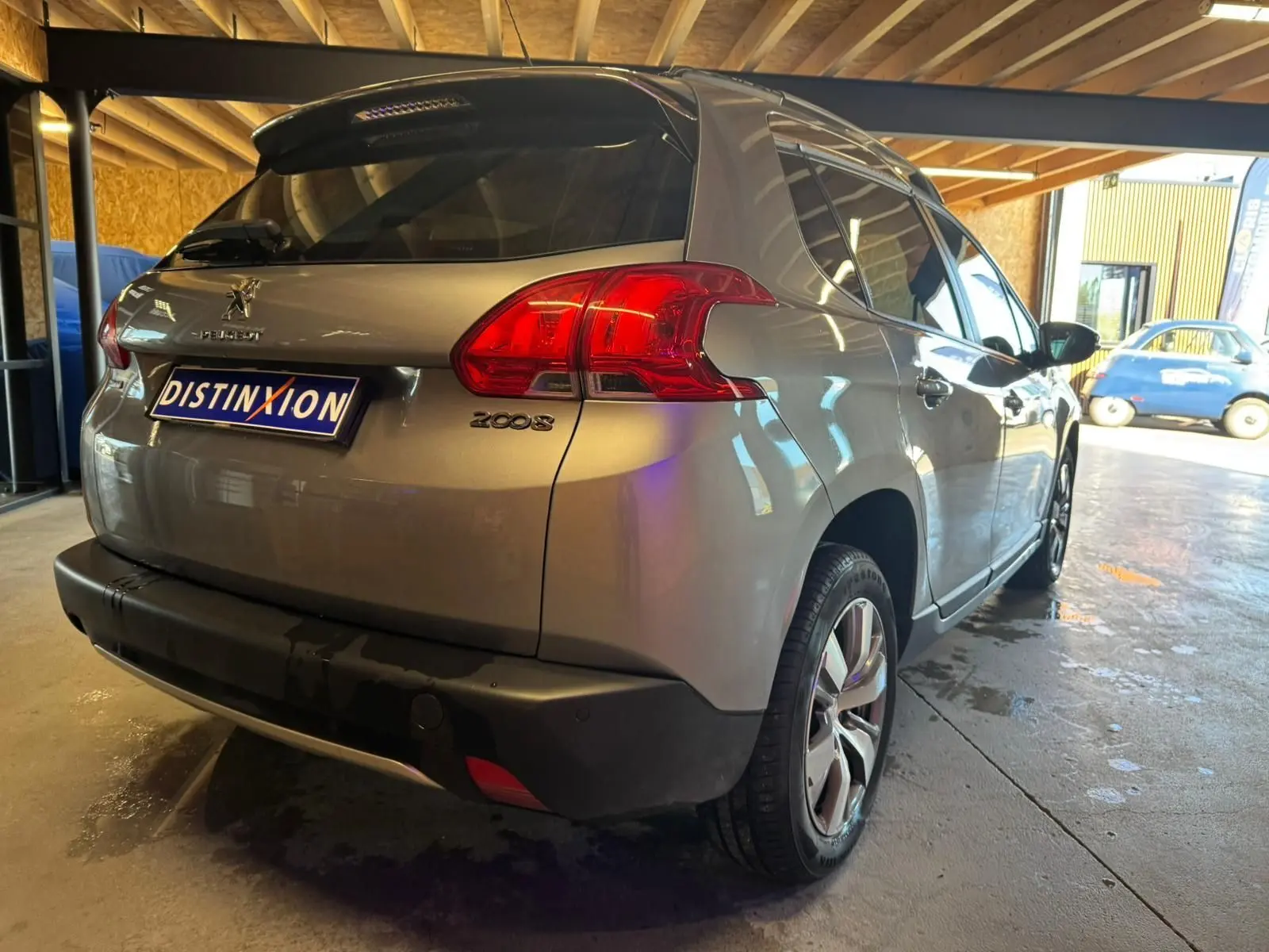 Vue 3/4 arrière droite d’un Peugeot 2008 gris métallisé, avec feux arrière rouges et jantes alliage visibles.