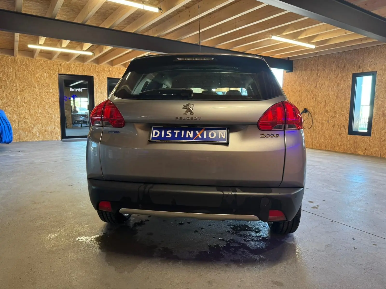 Vue arrière d’un Peugeot 2008 gris 2016 dans un garage avec plaque Distinxion visible.