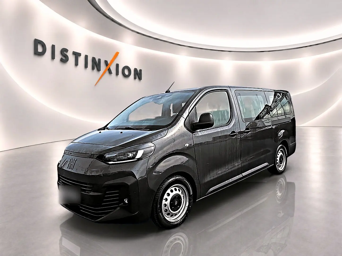 Fiat Scudo Combi gris titane en 3/4 avant droit, porte latérale coulissante visible, sur fond clair intérieur showroom.