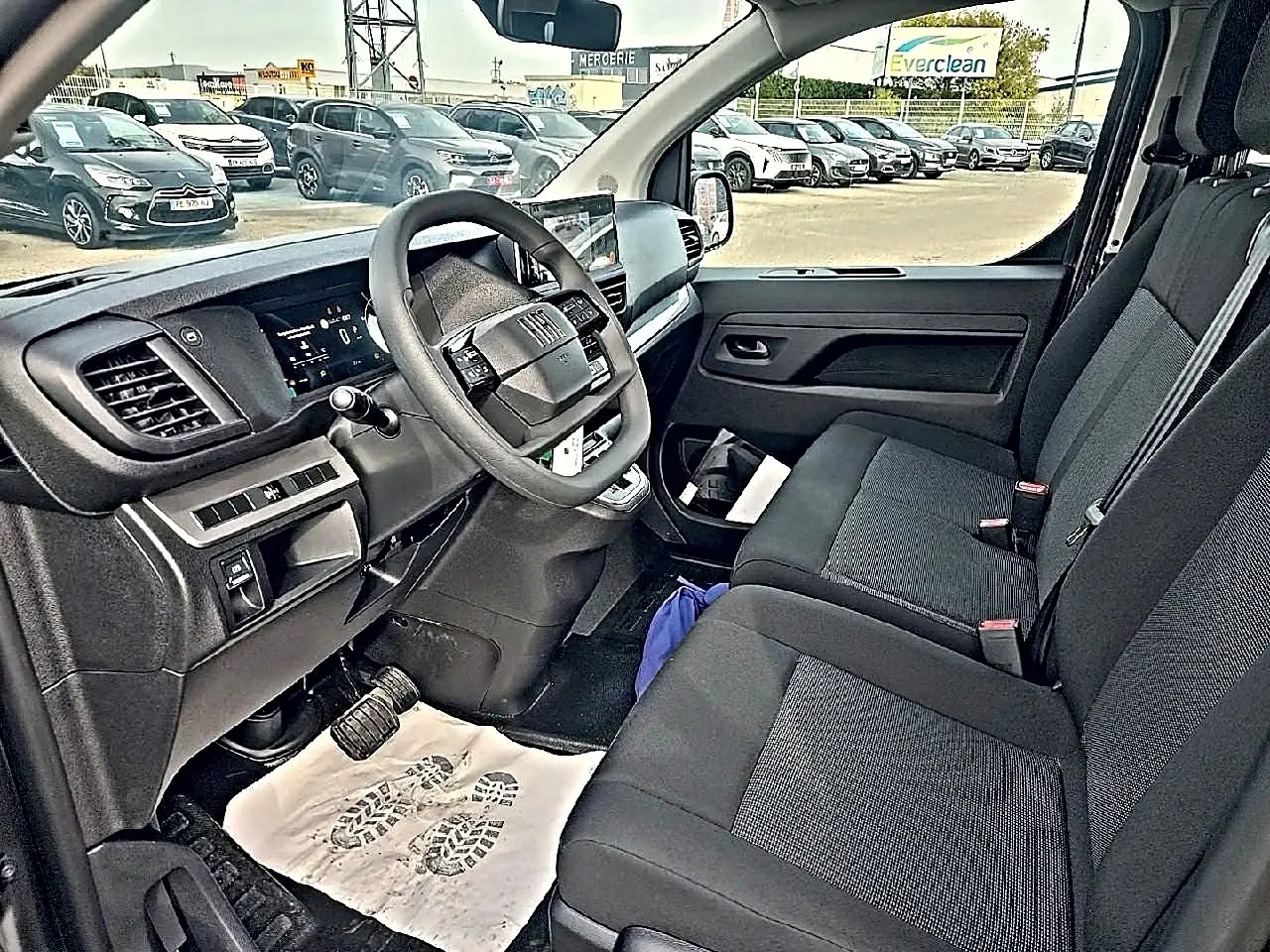 Vue intérieure côté conducteur du Fiat Scudo Combi gris titane, montrant le tableau de bord et la banquette avant noire bi-ton.