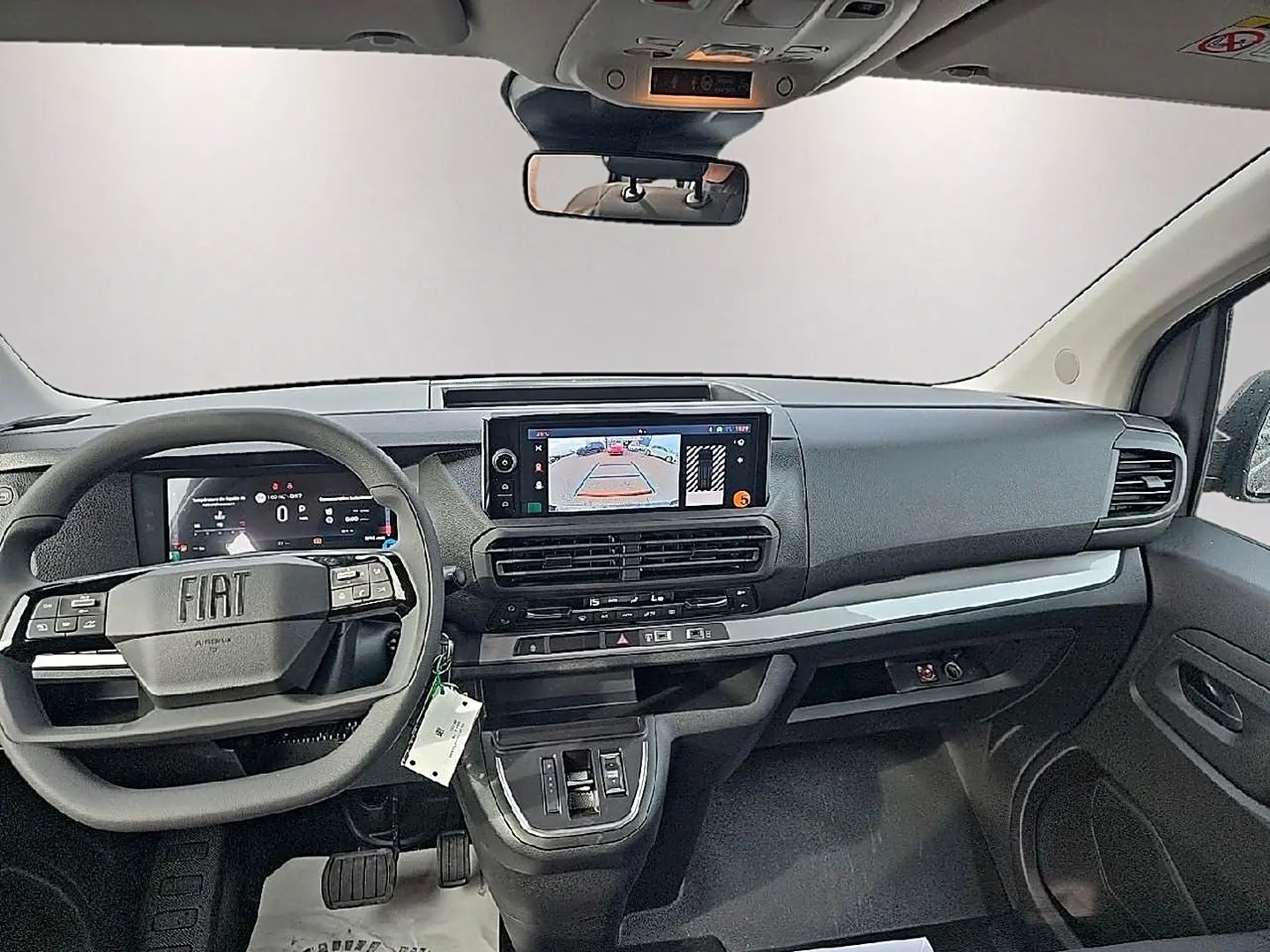 Vue intérieure avant du Fiat Scudo Combi gris titane 2026, tableau de bord moderne avec écran tactile et volant multifonctions.