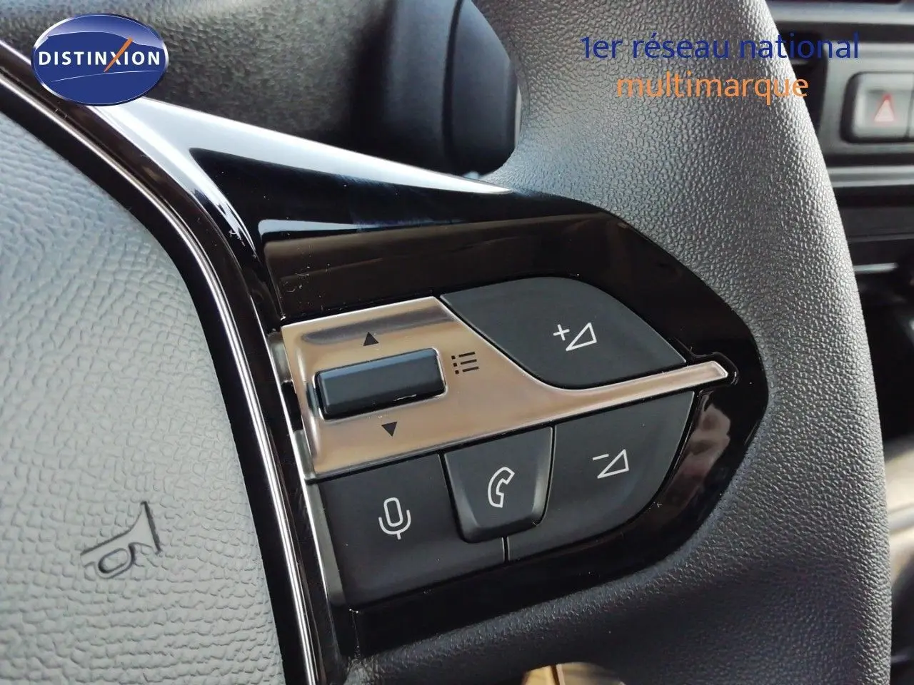 Gros plan sur les commandes multifonctions noires et argent du volant du Peugeot Partner blanc Kaolin, côté gauche.