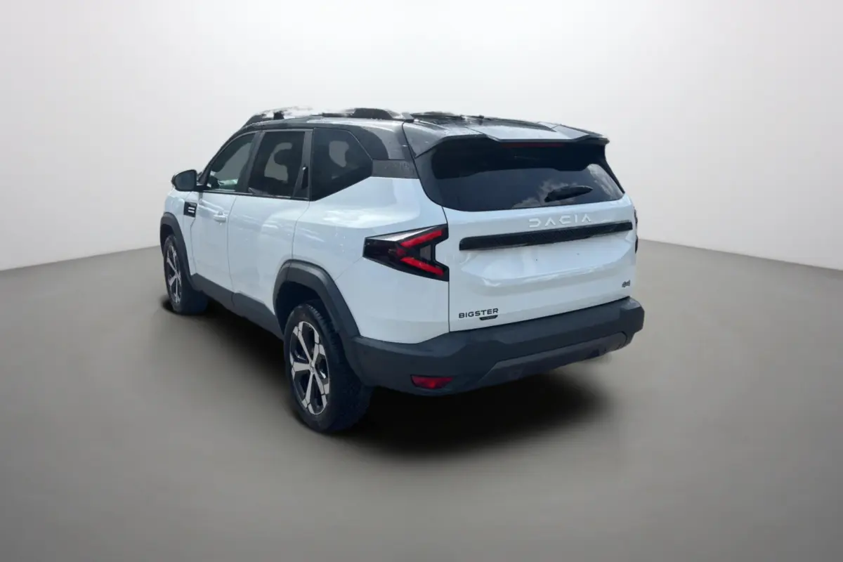 Vue 3/4 arrière droite du Dacia Bigster blanc à toit noir avec jantes alu 18 pouces et vitres surteintées.