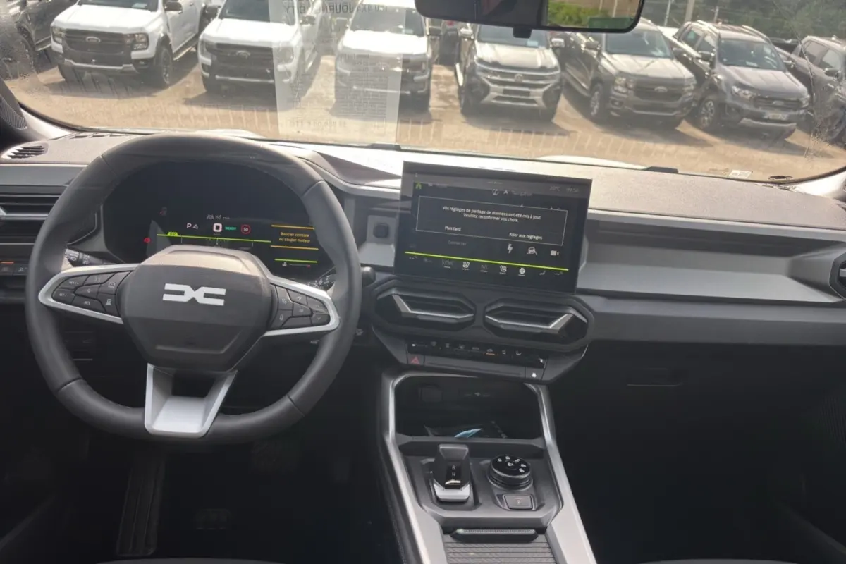 Vue intérieure avant du Dacia Bigster Hybrid 150 avec tableau de bord digital et écran tactile central.