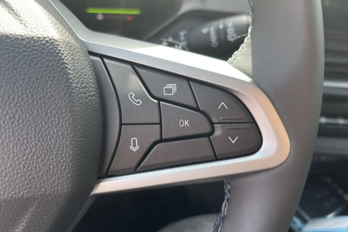 Gros plan sur les commandes multifonctions à droite du volant cuir du Dacia Bigster hybride blanc toit noir.