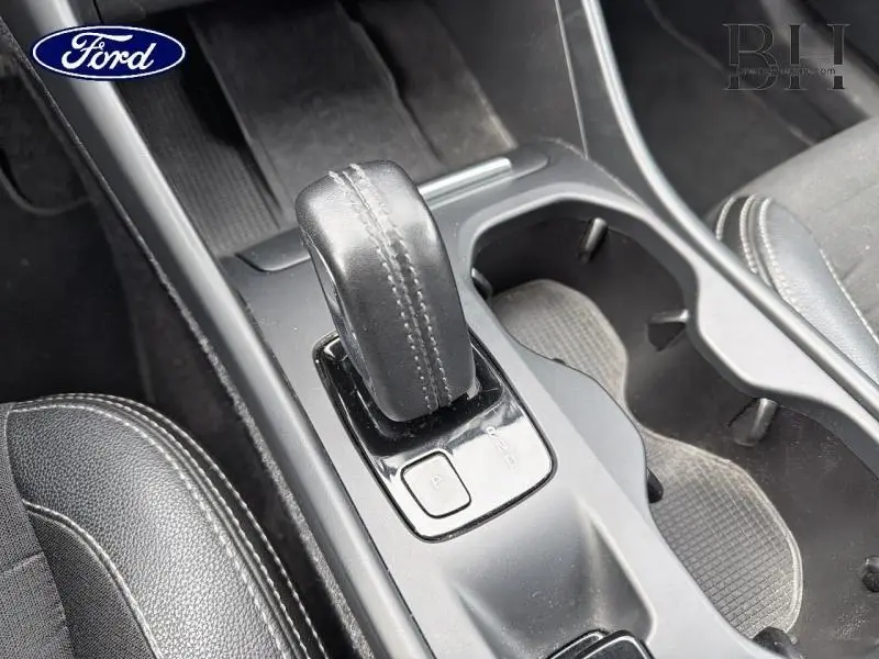 Gros plan sur le levier de vitesses automatique noir et les porte-gobelets du Volvo XC40 blanc Glace, intérieur moderne.