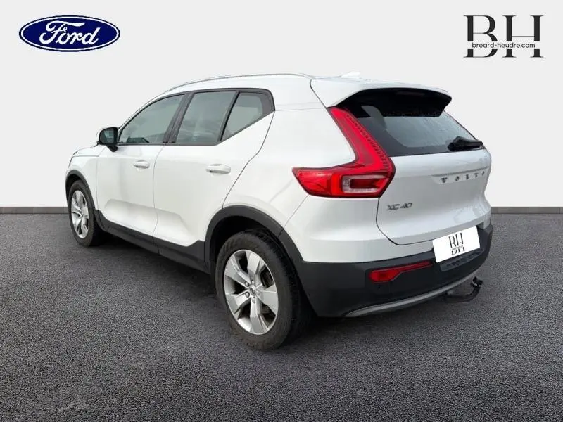 Vue 3/4 arrière droite d'un Volvo XC40 blanc Glace avec feux arrière en forme de L et jantes alliage.