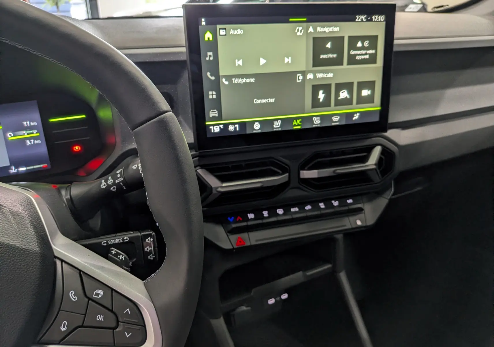 Vue intérieure du tableau de bord du Dacia Duster Hybrid-G 150 CH 4x4, écran tactile central et volant partiel visibles.