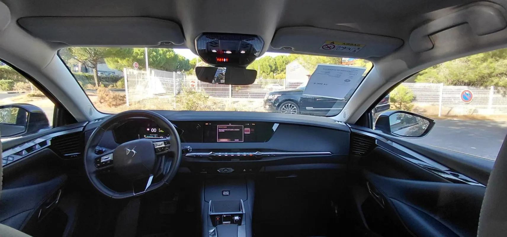 Vue intérieure avant du DS4 Hybride E-Tense gris 2024, avec tableau de bord digital et écran tactile central.