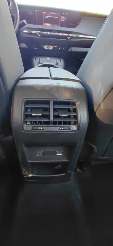 Vue intérieure arrière centrée sur la console centrale noire avec bouches d’aération et ports USB du DS4 Hybride E-Tense 2024.