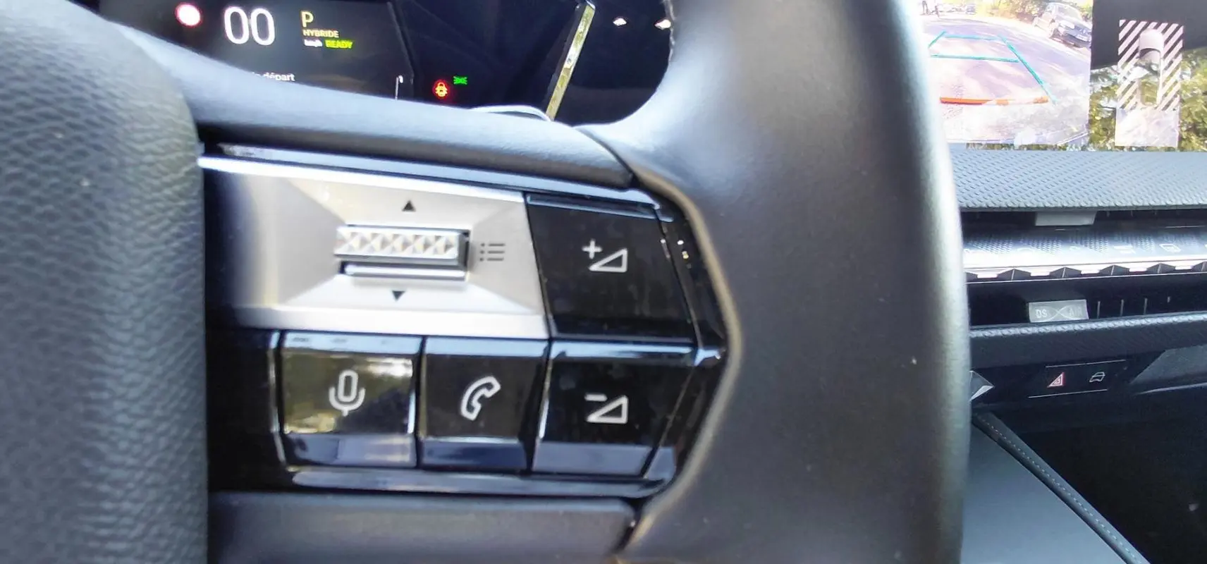 Gros plan sur les commandes au volant du DS4 Hybride E-Tense 225, avec écran tactile et caméra de recul visibles.