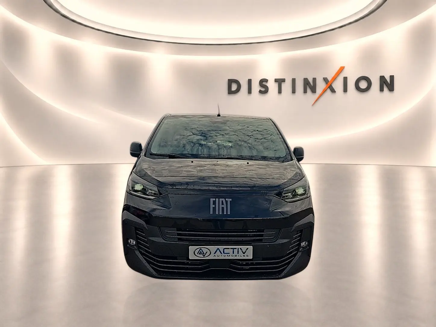 Vue avant d’un FIAT Scudo Combi noir 2026 avec calandre moderne et phares LED, sur fond lumineux intérieur.