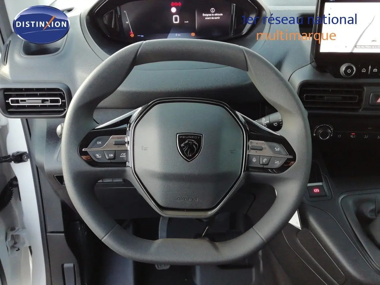 Vue intérieure centrée sur le volant multifonction du Peugeot Partner blanc Kaolin avec tableau de bord numérique.