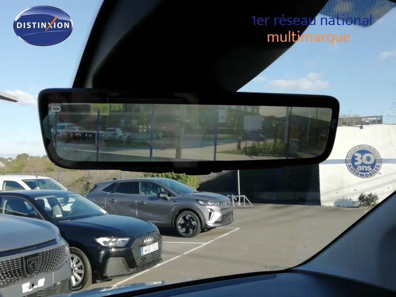 Vue intérieure du rétroviseur numérique d'un Peugeot Partner blanc Kaolin montrant le parking derrière le véhicule.