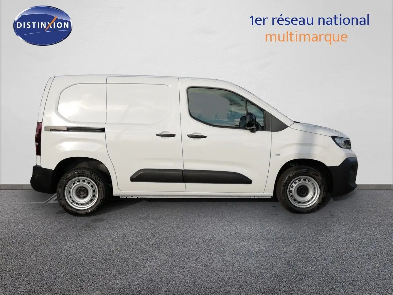 Vue de profil côté droit d’un Peugeot Partner blanc Kaolin, fourgon utilitaire avec protections noires sur les portières.