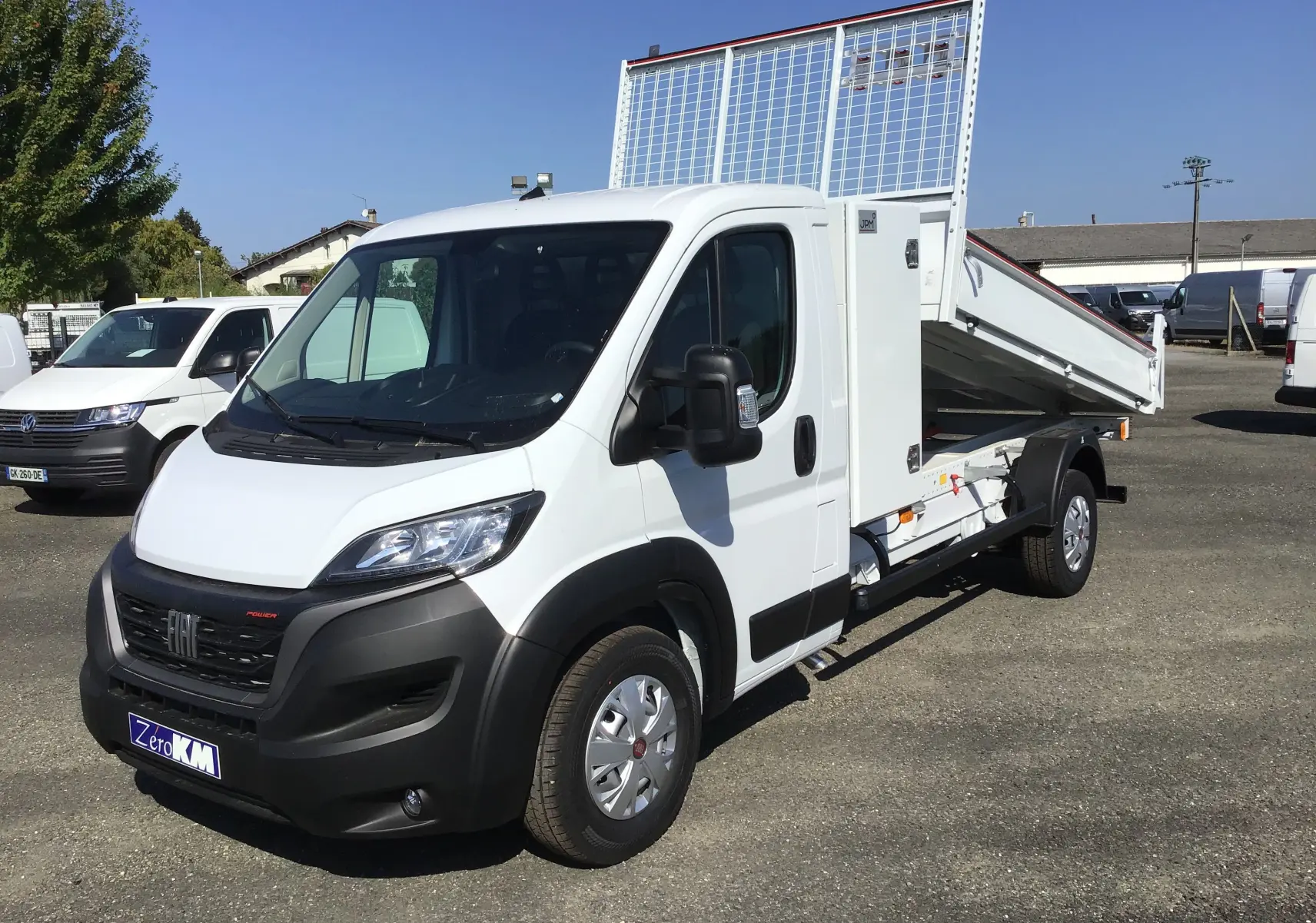 Fiat Ducato Chassis Benne blanc en 3/4 avant droit avec benne acier relevée et coffre latéral visible.