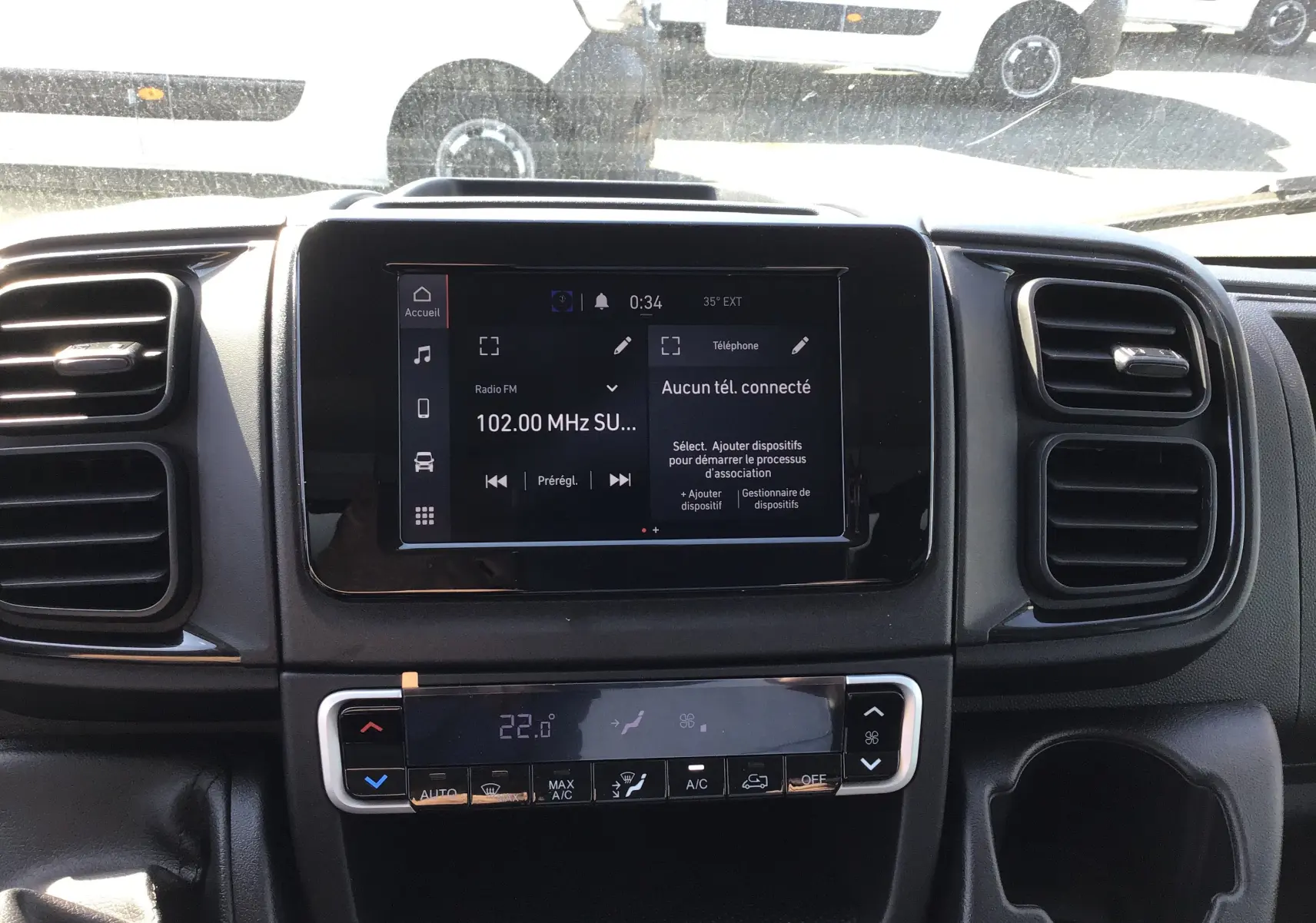 Vue intérieure centrée sur l'écran tactile et la console de climatisation du FIAT Ducato Chassis Benne blanc 2023.