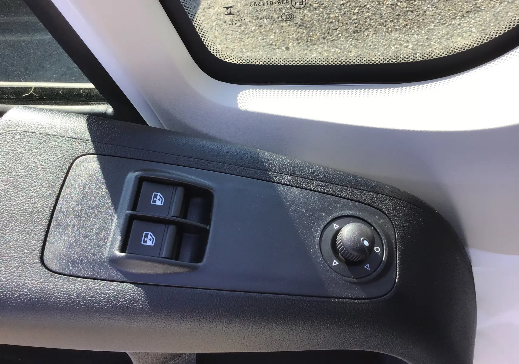 Gros plan sur les commandes de lève-vitres et réglage des rétroviseurs côté conducteur d'un Fiat Ducato blanc 2023.