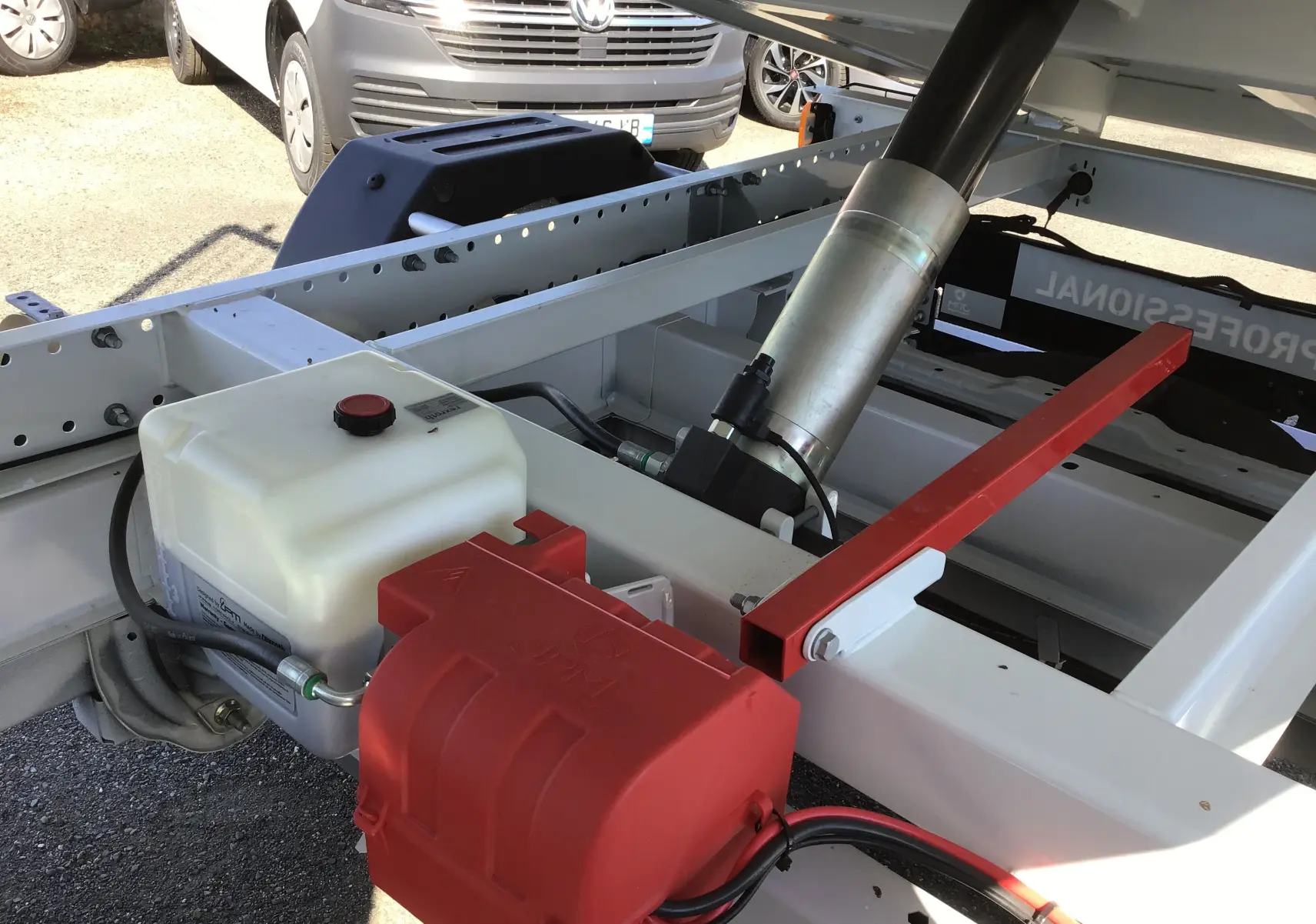 Gros plan sur la benne acier blanche du Fiat Ducato Chassis Benne 3T5, montrant le vérin hydraulique et le coffre rouge.