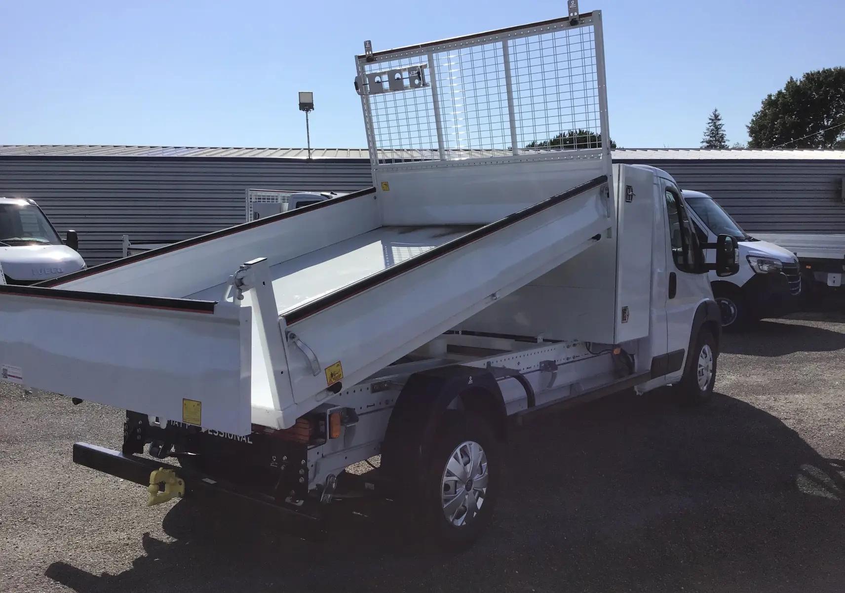 FIAT Ducato Chassis Benne blanc vu en 3/4 arrière droit avec benne acier relevée et coffre intégré.