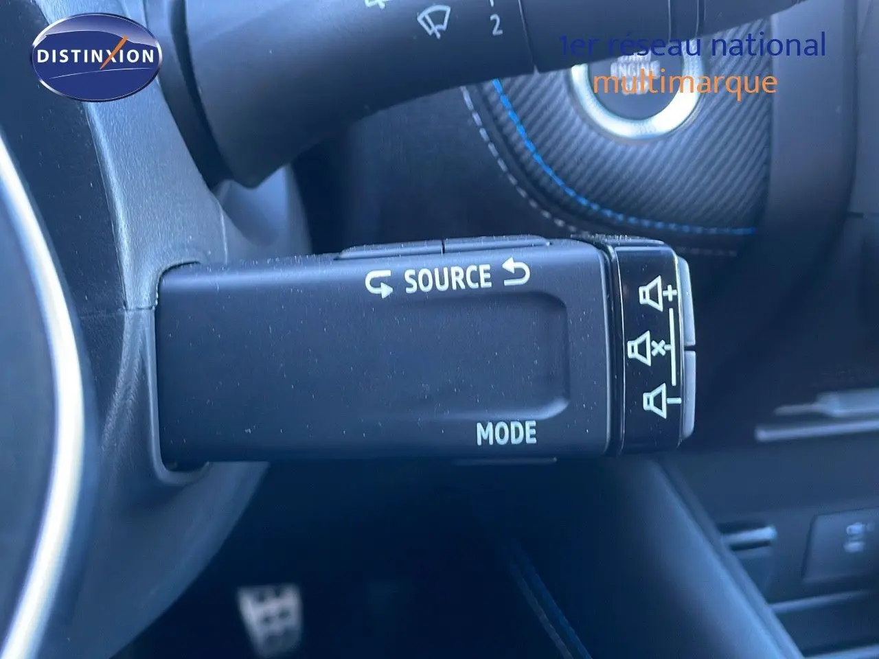 Gros plan sur la commande au volant du Renault Symbioz bleu iron metal, avec boutons source et mode visibles.