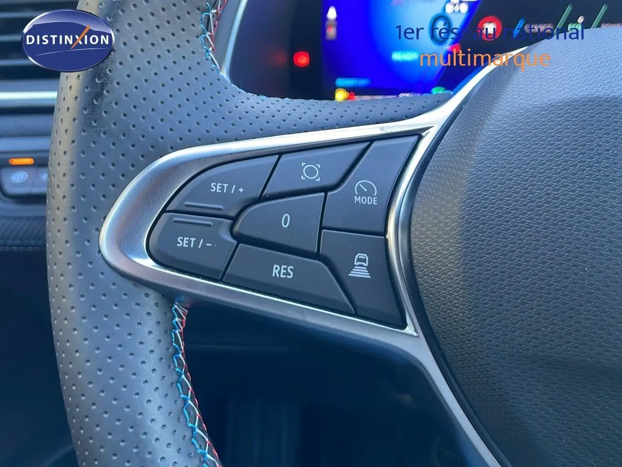 Gros plan sur les commandes du volant en cuir perforé avec surpiqûres tricolores du Renault Symbioz bleu Iron Metal.
