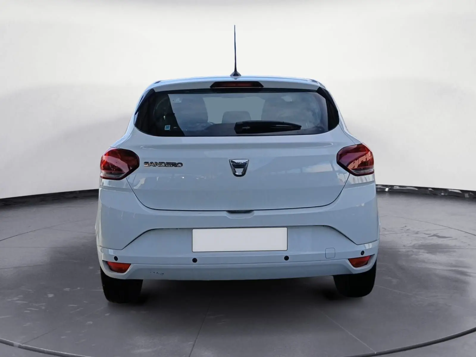 Vue arrière d'une Dacia Sandero blanche 2022, avec feux rouges et plaque Abeilhe Autos sur un parking extérieur.