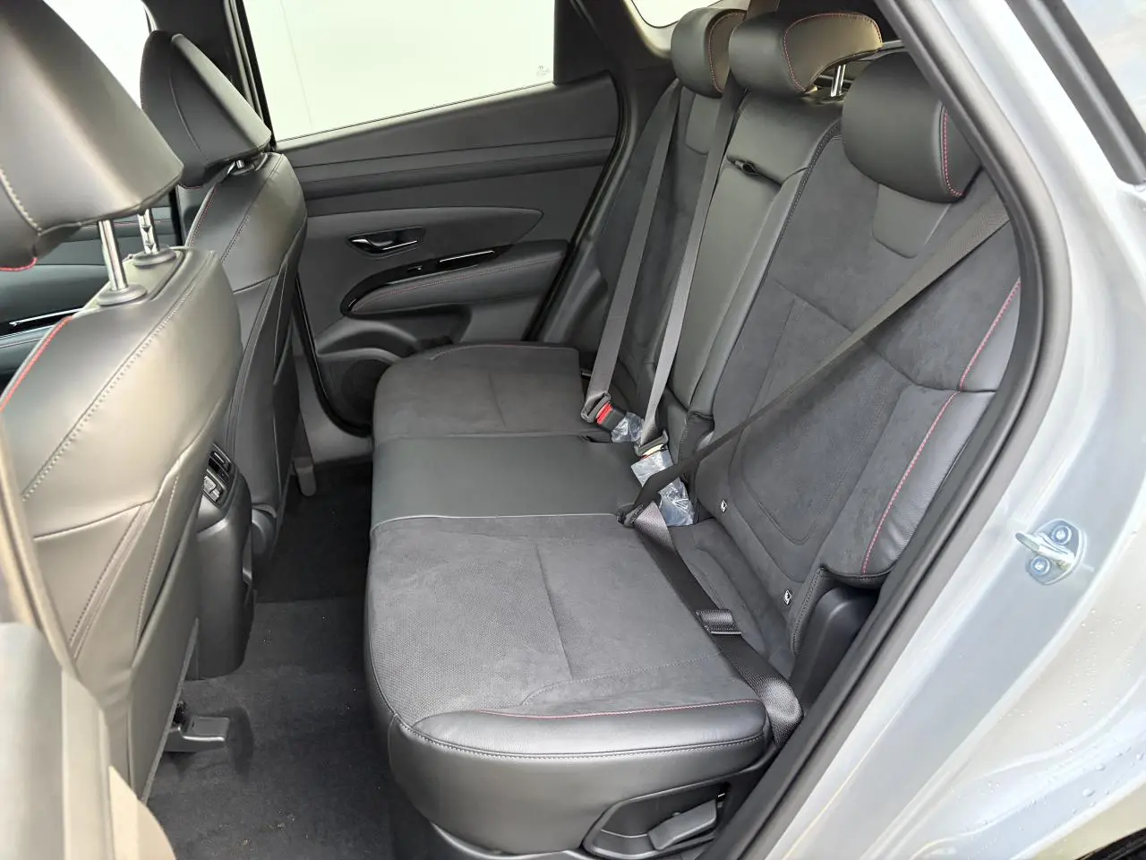 Vue intérieure côté droit des sièges arrière cuir/alcantara noirs avec surpiqûres rouges du Hyundai Tucson IV Shimmering Silver.