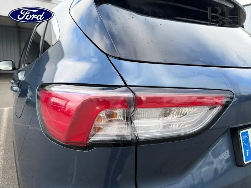 Gros plan sur le feu arrière droit d’un Ford Kuga 2022 bleu azur métallisé avec carrosserie brillante et vitres surteintées.
