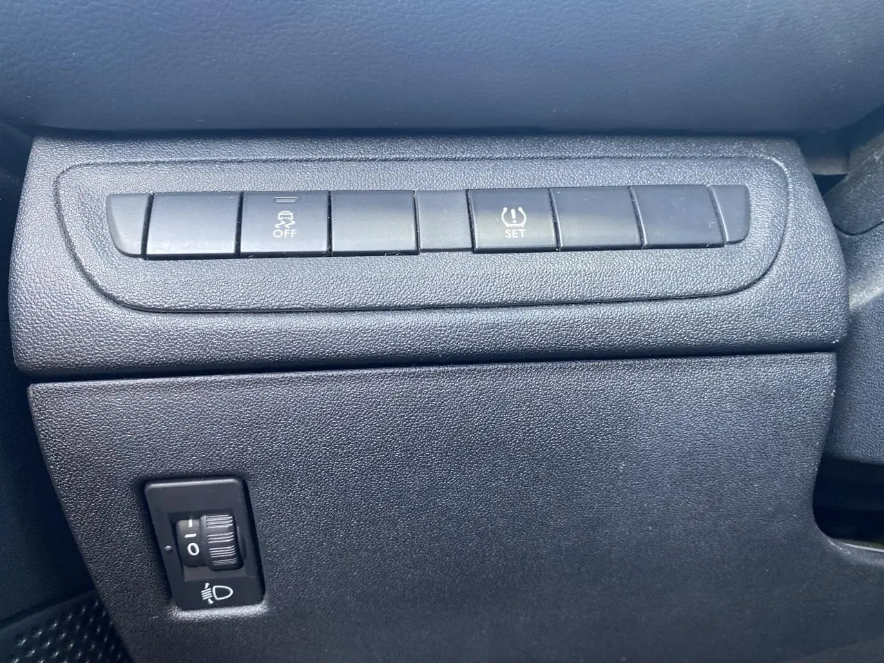 Gros plan sur les boutons de contrôle du tableau de bord de la Peugeot 208 gris foncé, avec réglage de stabilité et pression pneus.